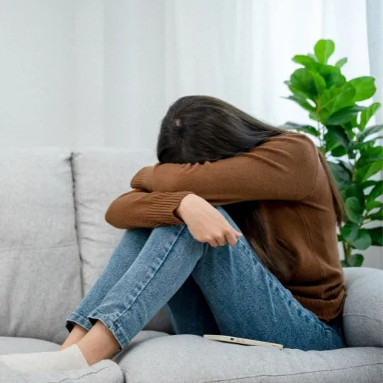 Chica encogida en el sofá